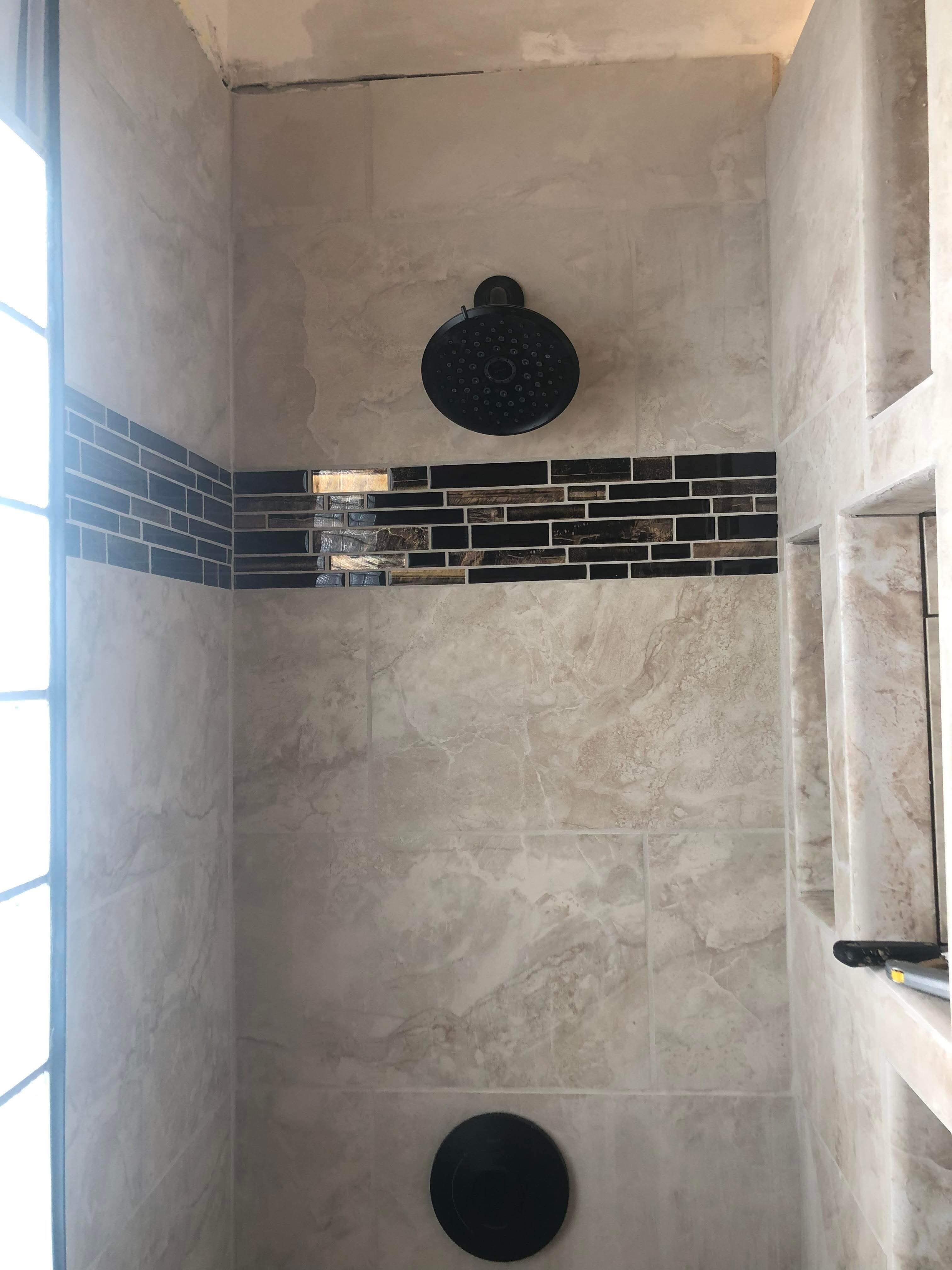 Custom tile shower with accent band and matte black fixtures
